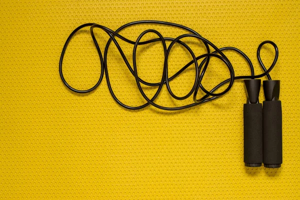 Vista superior de una cuerda de salto en la alfombra amarilla. Deporte en casa, práctica de fitness — Foto de Stock
