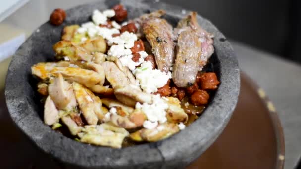 Preparazione di molcajete misti, carni diverse, formaggi freschi e pomodori arrosto con peperoncino servito in pietra vulcanica. — Video Stock