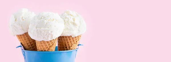 Conos de helado en un cubo azul sobre un fondo rosa. Un cono de helado al estilo oblea. Banner largo — Foto de Stock