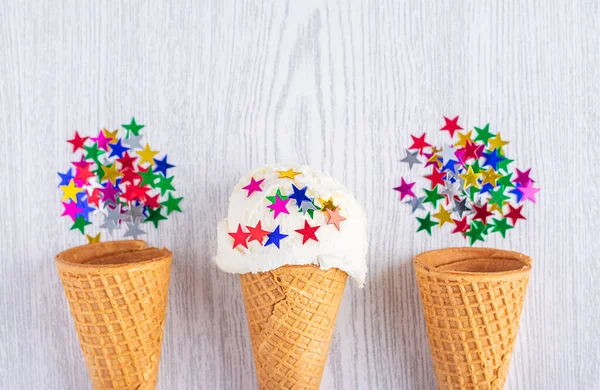 Conos de helado decorados con estrellas sobre un fondo de madera blanca. Un cono de helado al estilo oblea. Hora de verano . — Foto de Stock