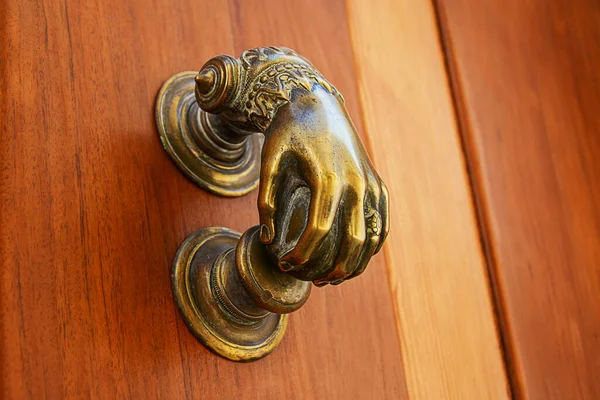 An antique metal door knob in form of a hand with ring and bracelet. Bronze hand shaped handle