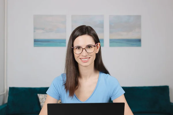 Close up view portrait smiling Caucasian young woman look at camera stand at home office table with laptop. Blogging
