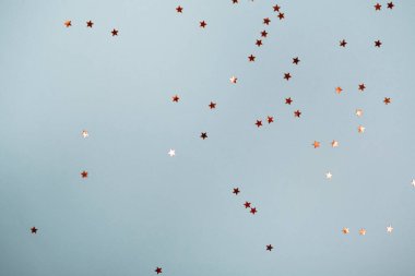 Pastel mavi renk şenlik arka planında altın yıldızların parıltısı konfetisi. Metin ve tasarım için kopyalama alanı olan düz stil.