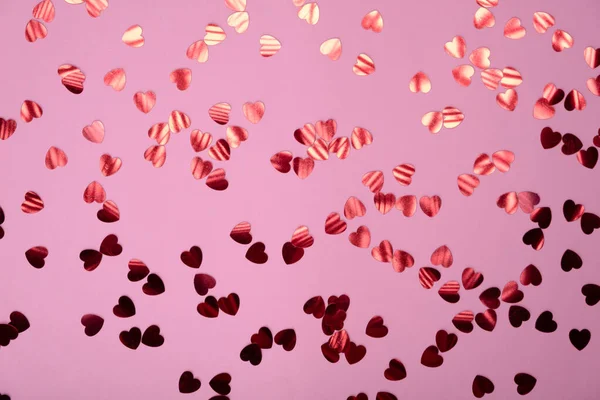 Fondo festivo de color rosa con confeti en forma de corazón rojo. Estilo San Valentín plano con espacio de copia para texto, diseño —  Fotos de Stock