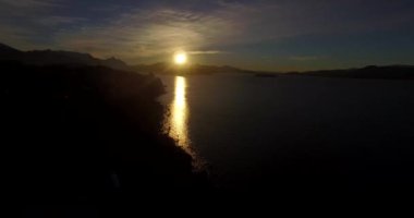 Dağın tepesindeki güneş, sarı ışığını Nahuel Huapi Gölü 'ne yansıtıyor.