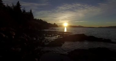 Dağın tepesindeki güneş, sarı ışığını Nahuel Huapi Gölü 'ne yansıtıyor.