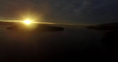 Dağın tepesindeki güneş, sarı ışığını Nahuel Huapi Gölü 'ne yansıtıyor.