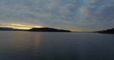 Bariloche 'deki Nahuel Huapi gölünün kıyısından başlayan hava manzarası. Dağlar ve kışın soğuk günbatımı olan küçük bir ada..