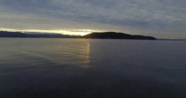 Bariloche 'deki Nahuel Huapi gölünün kıyısından başlayan hava manzarası. Dağlar ve kışın soğuk günbatımı olan küçük bir ada..