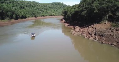 Misiones Arjantin 'de bir nehri geçen sürat teknesinin hava görüntüsü bir yaz günü doğa, ağaçlar ve faunayla çevrili.