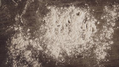 Tahta bir masanın üzerine un serpiştirilmiş. 