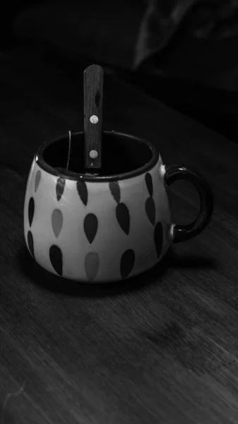 Bir fincan çay, içinde kaşık olan ahşap bir masanın üzerinde.