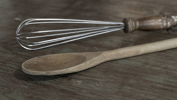 A whisk and a wood spoon over a table