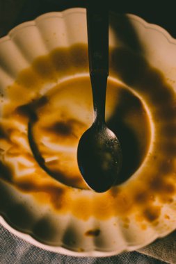 Üzerinde kaşık olan kirli bir karamelli tatlı tabağı..