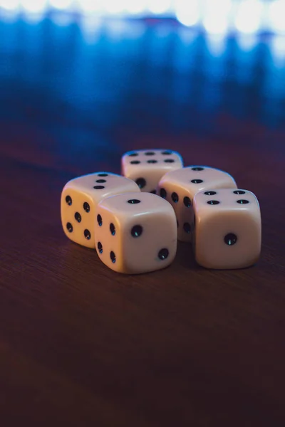 Dices over a table with bright lights behind. with numbers one, two, three, four and six.