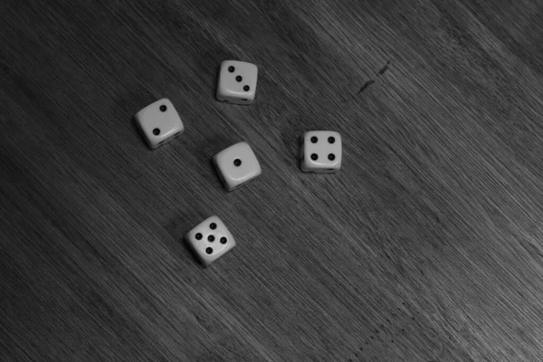 Dices over a wood table with numbers two, three, four, five and one.