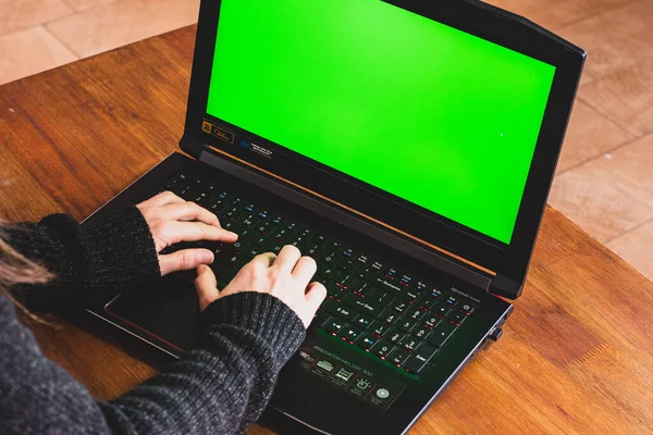 A women typing on a notebook doing home office with a green screen. With a Plant on the table