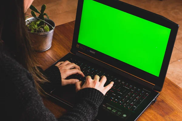 A women typing on a notebook doing home office with a green screen.