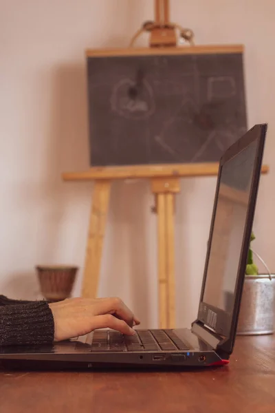 A women typing on a notebook doing home office with a green screen. with a blackboard behind