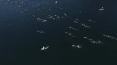 Güneşli bir yaz gününde Nahuel Huapi Gölü 'nü geçen Ironman triatlon yarışmasında yüzücülerin hava görüntüsü. Dağlar ve bitki örtüsüyle çevrili