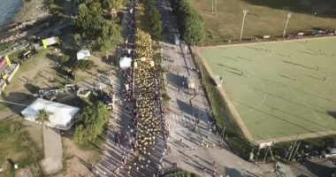 Birçok koşucu Buenos Aires şehrinde bir maratonda koşuyor, güneşli bir yaz gününde şehrin ortasındaki bir sokaktan geçiyor Arjantin 'in Vicente Lopez bölgesinde nehir ve çevresi doğa ile çevrili..