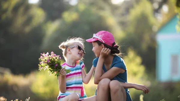 Two Cute Sisters Blonde Brunette Sitting Ground Chatting Widflowers Bouquet — Stock Photo, Image
