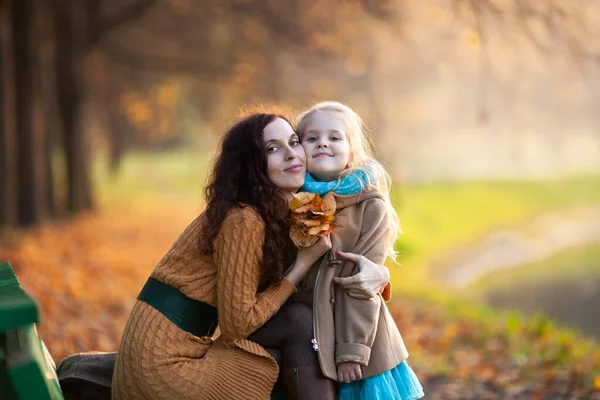 Mała Blondynka Przytulająca Się Mamą Trzymającą Bukiet Jesiennych Liści Koncepcja — Zdjęcie stockowe