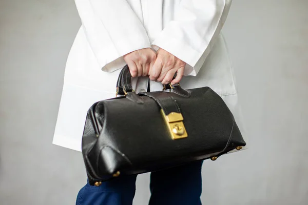 Female physician holding a black leather doctor's bag heading to the office to practice medicine