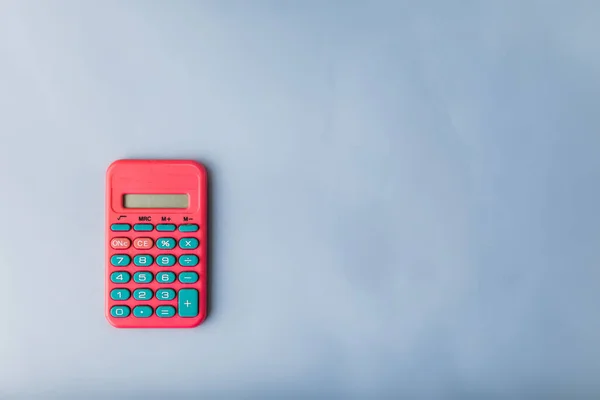 hot pink vintage retro calculator on a blue surface with copy space