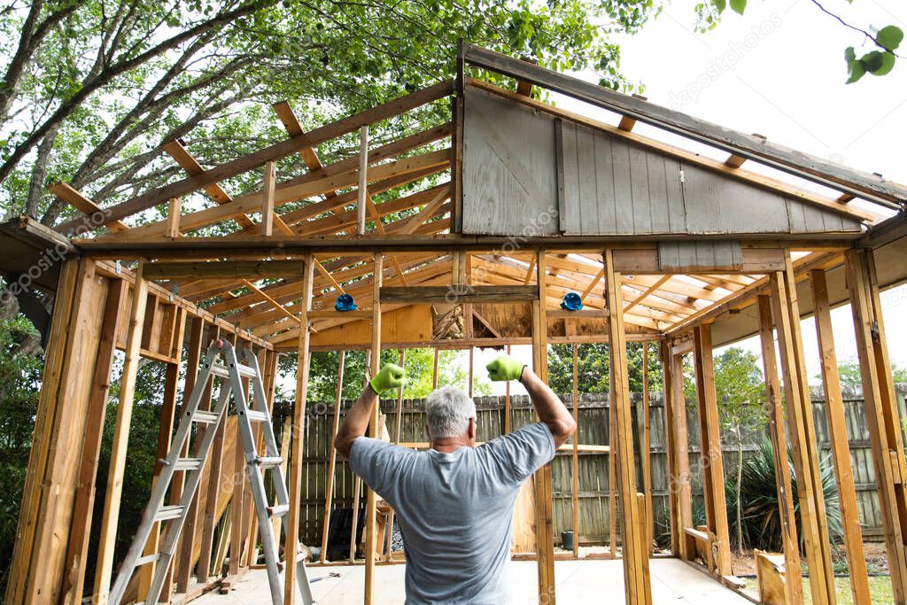 strong older man making muscles with his arms after the demolition of a building