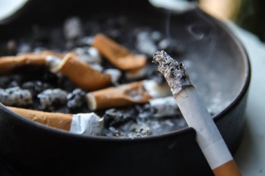 Kül tablası dolusu füme sigara, kül tablası dolusu sigara izmariti, bağımlılık, sağlıksız yaşam konsepti. 