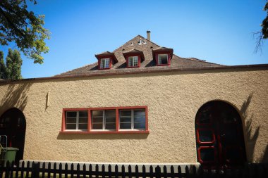 Pencereleri ve kemerli kapısı olan sarı binanın ayrıntıları çatıda küçük pencereler güneşli bir günde Zürih 'te göl kenarında mavi gökyüzü olan bir bina.