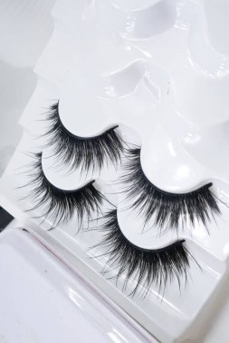 Güzel, uzun, siyah, takma kirpiklerin yakın çekimi, beyaz plastik tutacakta yapay kirpikler, kopyalama alanı. 