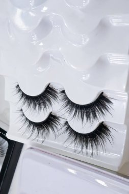 Güzel, uzun, siyah, takma kirpiklerin yakın çekimi, beyaz plastik tutacakta yapay kirpikler, kopyalama alanı. 