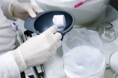 Güzellik salonunda beyaz eldivenli bir kozmetikçi yüz bakımı için havyarın maskesini çıkartıyor. 