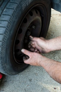 Kirli mekanik ellerinin aşırı yakın çekim eski araba lastiği vidaları öğütüyor, araba lastiklerini değiştiriyor ve tamir ediyor.  