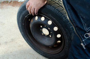 Otomobil tamircisi eski siyah lastik lastik tutuyor, kapatılıyor, araba servisi, onarım, bakım konsepti 