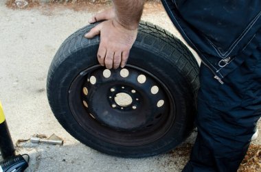 Otomobil tamircisi eski siyah lastik lastik tutuyor, kapatılıyor, araba servisi, onarım, bakım konsepti 