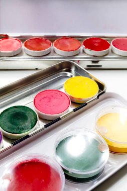 Beyaz arkaplanda, dikey görüntüde izole edilmiş metal kutularda renkli göz falı paleti, kapat