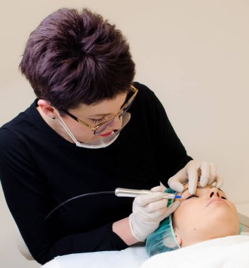 Kalıcı makyaj dövmesi, kalıcı göz kalemi yapan güzellik uzmanı, güzellik salonundaki genç bir kadının göz kalemi dövmesi prosedürü.,