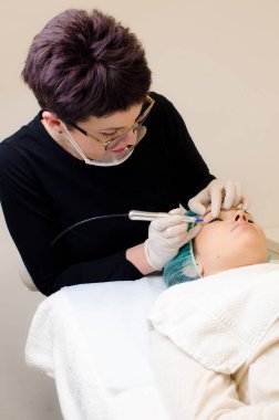 Kalıcı makyaj dövmesi, kalıcı göz kalemi yapan güzellik uzmanı, güzellik salonundaki genç bir kadının göz kalemi dövmesi prosedürü.,