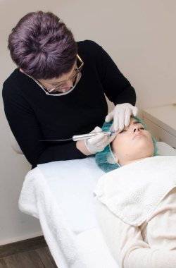 Kalıcı makyaj dövmesi, kalıcı göz kalemi yapan güzellik uzmanı, güzellik salonundaki genç bir kadının göz kalemi dövmesi prosedürü.,