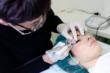 Kalıcı makyaj dövmesi, kalıcı göz kalemi yapan güzellik uzmanı, güzellik salonundaki genç bir kadının göz kalemi dövmesi prosedürü.,