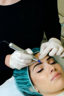 Kalıcı kaş makyajı yapan kozmetikçi. Güzellik salonunda genç bir kadının dövmesi var. Yakın plan. 