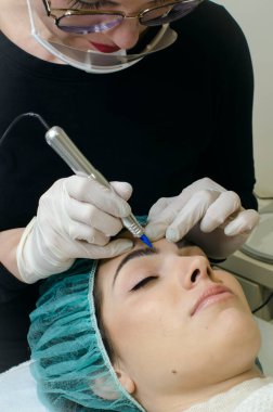 Kalıcı kaş makyajı yapan kozmetikçi. Güzellik salonunda genç bir kadının dövmesi var. Yakın plan. 