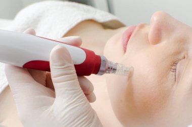 Kozmetik uzmanı, beyaz eldivenli güzellik uzmanı güzellik salonundaki genç kız müşteriye yüz derisi tedavisi uyguluyor. Kozmetoloji ve profesyonel cilt bakımı, arka görüş. 