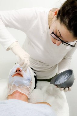 Güzellik uzmanı güzellik salonundaki kadın müşteriye yüz bakımı için kozmetik havyarı soyuyormuş.