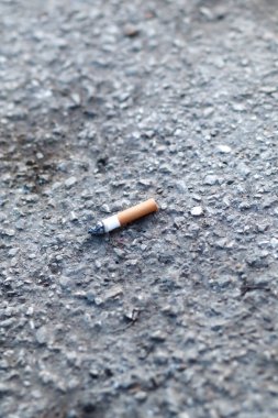 burning cigarette butt, single, isolated on concrete. Cigarette on pavement, close up, top view 