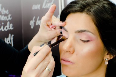 Makyaj sanatçısı cımbızla çalışıyor. Güzellik stüdyosundaki bayan müşteriye takma siyah kirpik takıyor. Kapat. 