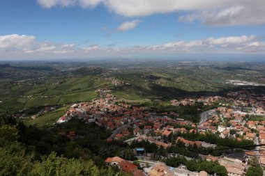 İtalya 'nın San Marino kentindeki Titano Dağı' ndaki Guaita Kalesi 'nin tepesinden panoramik manzara güneşli bir günde bulutlarla kaplı güzel mavi gökyüzü. Denize, San Marino köylerine ve Rimini 'ye bakın.,